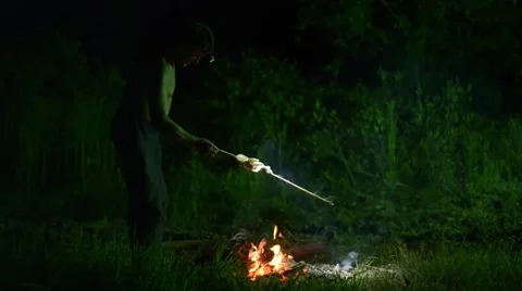 Man Roasts A Fish On Fire In The Evening Stock Footage 40402154