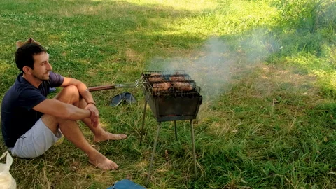 A man roasts meat on a fire outdoors. Elective focus. Stock Footage 293338984