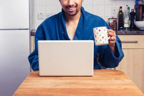 Man in robe checking emails and having coffee Stock-Fotos