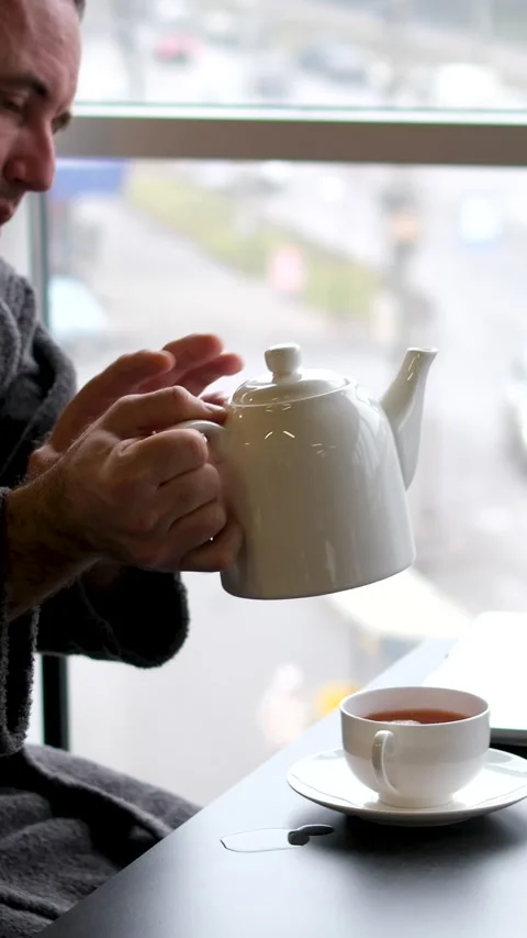 A man in a robe drinks tea after a bath Sleepy casual young man wearing bathrobe Stock Footage 302066547