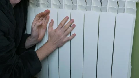 Man In Robe Warms Hands On Central Heating Radiator Stock Footage 329403060