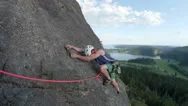 Man Rock Climbing On Top Rope Up Mountain Overlooking Valley With Lake Stock Footage