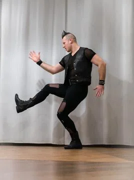A man in rock clothes performs dance moves. A metal man with a mohawk on hi.. Stock Photos