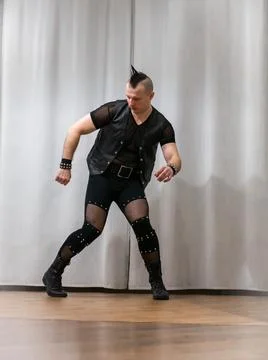 A man in rock clothes performs dance moves. A metal man with a mohawk on hi.. Stock Photos
