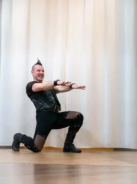 A man in rock clothes performs dance moves. A metal man with a mohawk on hi.. Stock Photos