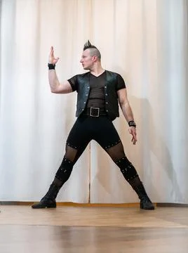 A man in rock clothes performs dance moves. A metal man with a mohawk on hi.. Stock Photos