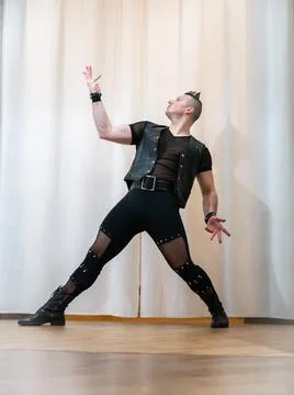 A man in rock clothes performs dance moves. A metal man with a mohawk on hi.. Stock Photos