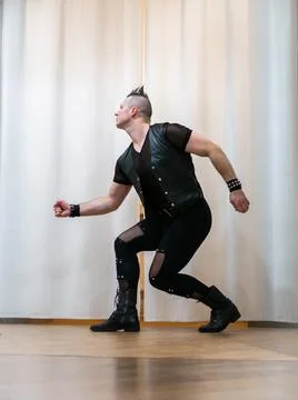 A man in rock clothes performs dance moves. A metal man with a mohawk on hi.. Stock Photos