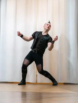 A man in rock clothes performs dance moves. A metal man with a mohawk on hi.. Stock Photos