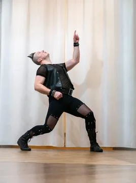 A man in rock clothes performs dance moves. A metal man with a mohawk on hi.. Stock Photos
