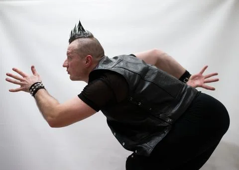 A man in rock clothes performs dance moves. A metal man with a mohawk on hi.. Stock Photos