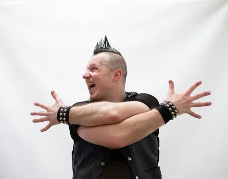 A man in rock clothes performs dance moves. A metal man with a mohawk on hi.. Stock Photos
