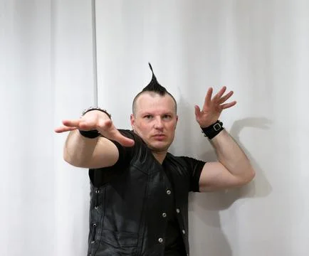 A man in rock clothes performs dance moves. A metal man with a mohawk on hi.. Foto stock