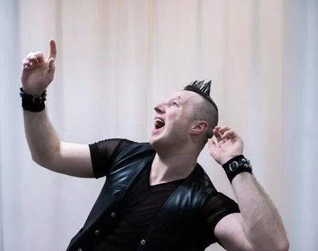 A man in rock clothes performs dance moves. A metal man with a mohawk on hi.. Stock Photos