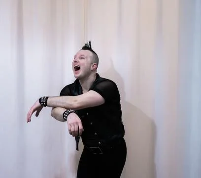 A man in rock clothes performs dance moves. A metal man with a mohawk on hi.. Stock Photos