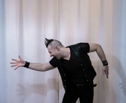 A man in rock clothes performs dance moves. A metal man with a mohawk on hi.. Stock Photos
