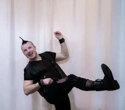 A man in rock clothes performs dance moves. A metal man with a mohawk on hi.. Stock Photos