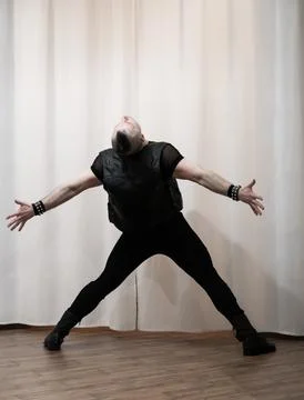 A man in rock clothes performs dance moves. A metal man with a mohawk on hi.. Stock Photos