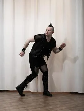 A man in rock clothes performs dance moves. A metal man with a mohawk on hi.. Stock Photos