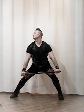A man in rock clothes performs dance moves. A metal man with a mohawk on hi.. Stock Photos