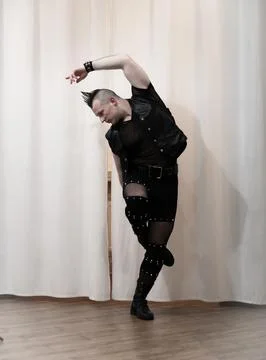 A man in rock clothes performs dance moves. A metal man with a mohawk on hi.. Stock Photos