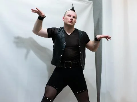 A man in rock clothes performs dance moves. A metal man with a mohawk on hi.. Photos