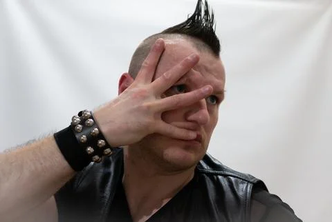 A man in rock clothes performs dance moves. A metal man with a mohawk on hi.. Stock Photos