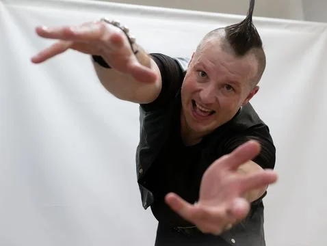 A man in rock clothes performs dance moves. A metal man with a mohawk on hi.. Stock Photos