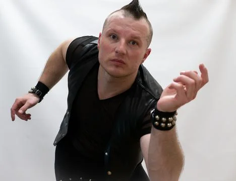 A man in rock clothes performs dance moves. A metal man with a mohawk on hi.. Stock Photos