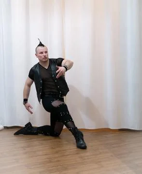 A man in rock clothes performs dance moves. A metal man with a mohawk on hi.. Stock Photos