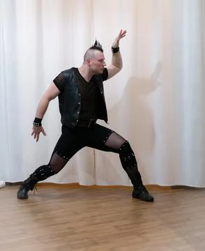 A man in rock clothes performs dance moves. A metal man with a mohawk on hi.. Stock Photos
