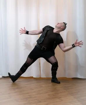 A man in rock clothes performs dance moves. A metal man with a mohawk on hi.. Stock Photos