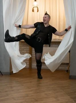 A man in rock clothes performs dance moves. A metal man with a mohawk on hi.. Stock Photos