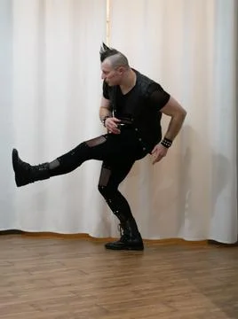 A man in rock clothes performs dance moves. A metal man with a mohawk on hi.. Stock Photos