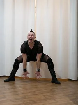 A man in rock clothes performs dance moves. A metal man with a mohawk on hi.. Stock Photos
