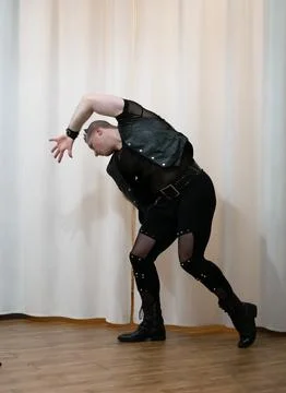 A man in rock clothes performs dance moves. A metal man with a mohawk on hi.. Stock Photos