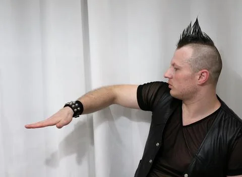A man in rock clothes performs dance moves. A metal man with a mohawk on hi.. Stock Photos