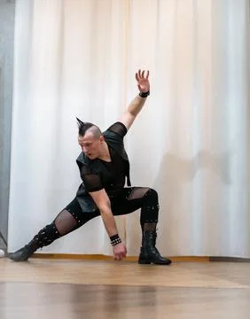 A man in rock clothes performs dance moves. A metal man with a mohawk on hi.. Stock Photos