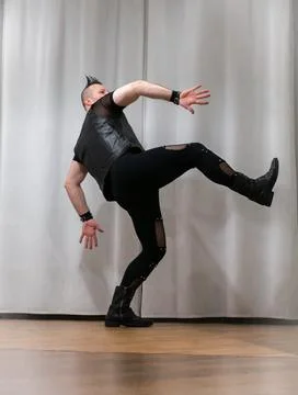 A man in rock clothes performs dance moves. A metal man with a mohawk on hi.. Stock Photos