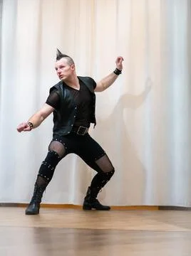 A man in rock clothes performs dance moves. A metal man with a mohawk on hi.. Stock Photos