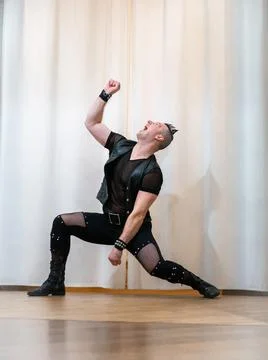 A man in rock clothes performs dance moves. A metal man with a mohawk on hi.. Stock Photos