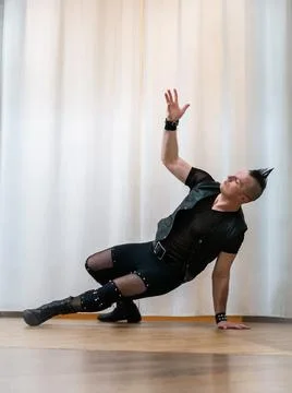 A man in rock clothes performs dance moves. A metal man with a mohawk on hi.. Stock Photos