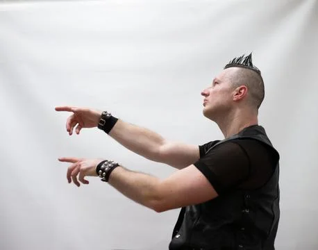 A man in rock clothes performs dance moves. A metal man with a mohawk on hi.. Foto stock