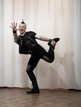 A man in rock clothes performs dance moves. A metal man with a mohawk on hi.. Foto stock