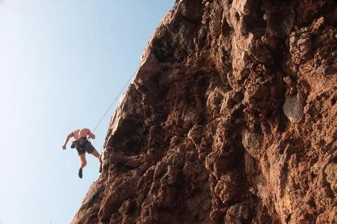 Man rock rappelling down red rock hillside Stock Photos