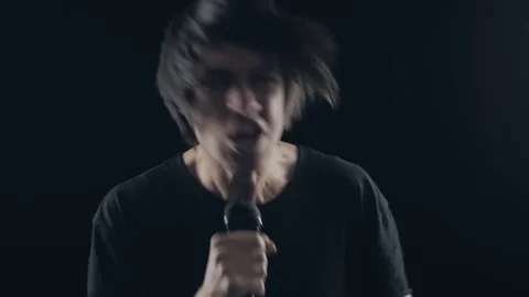 Man rock singer sings into a microphone And shakes his head on a black Stock Footage