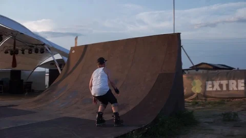Man on roller skates drives in on a springboard and falls Video stock 102775928