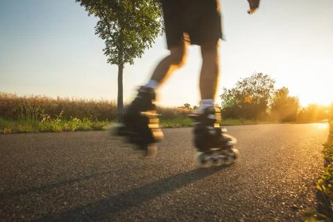 Man roller skating on the cycle path during lovely summer sunset, sport concept 库存照片