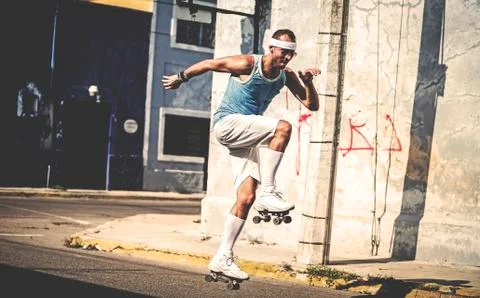 A man rollerskating with one leg raised in a street. Foto stock