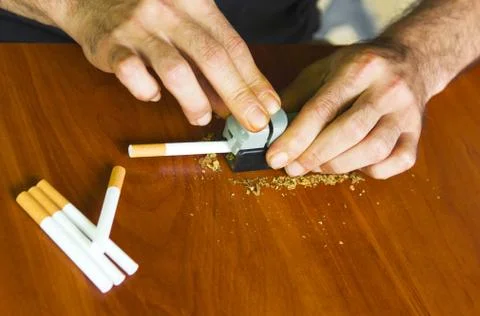 Man rolling cigarettes using fresh tobacco Stock Photos